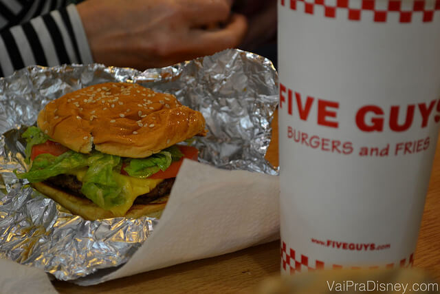 Foto do hambúrguer do Five Guys em Orlando, com um copo de refrigerante ao lado 