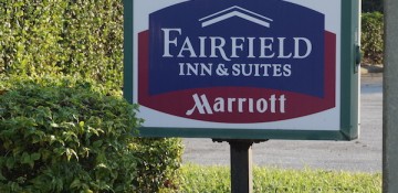 Foto da placa na entrada do hotel Fairfield Inn & Suites by Marriott, com as cores do Marriott (azul e vinho)