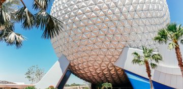 Imagem que mostra a bola do Epcot em um dia de céu azul, com visitantes passando embaixo e ao redor dela.