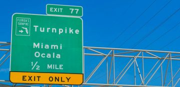 Foto da placa da saída para a Turnpike (a placa diz "Exit 77/Turnpike Miami Ocala 1/2 mile")