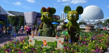 Foto de topiárias do Mickey e da Minnie, com a bola do Epcot atrás, durante o Flower & Garden Festival no parque