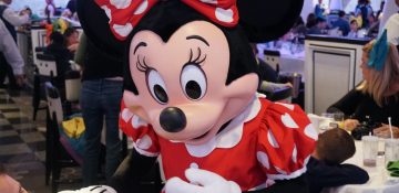 Foto da Minnie interagindo com visitantes em uma refeição com personagens