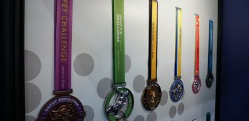 Foto de diversas medalhas que são entregues aos participantes da Maratona da Disney, com cordões de cores variadas