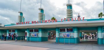 Foto da entrada do Hollywood Studios, que é pintada de azul com o nome do parque acima em vermelho.