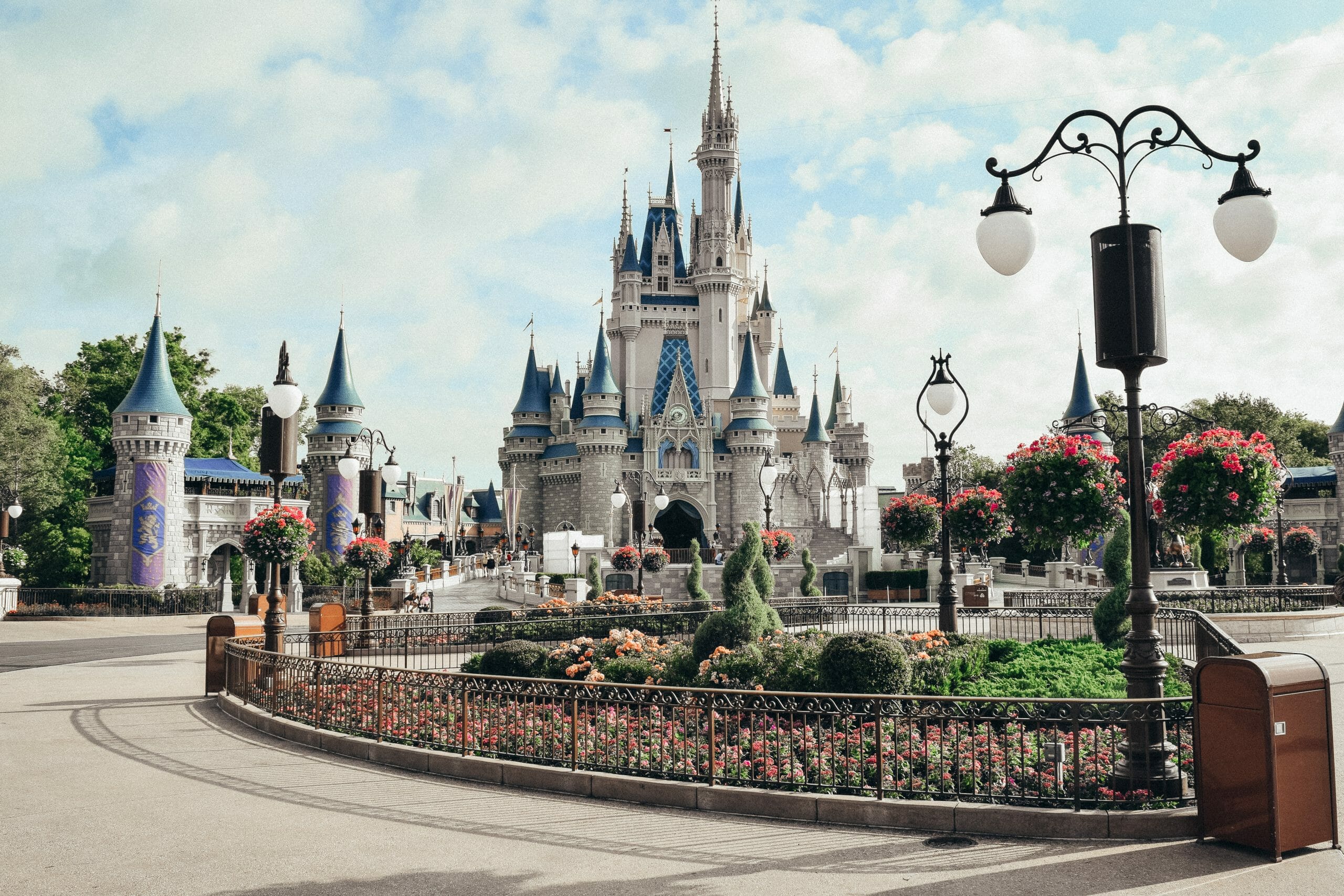 Foto da Main Street do Magic Kingdom, mostrando o canteiro que fica em frente ao castelo e o Castelo da Cinderela ao fundo, com o céu claro atrás.