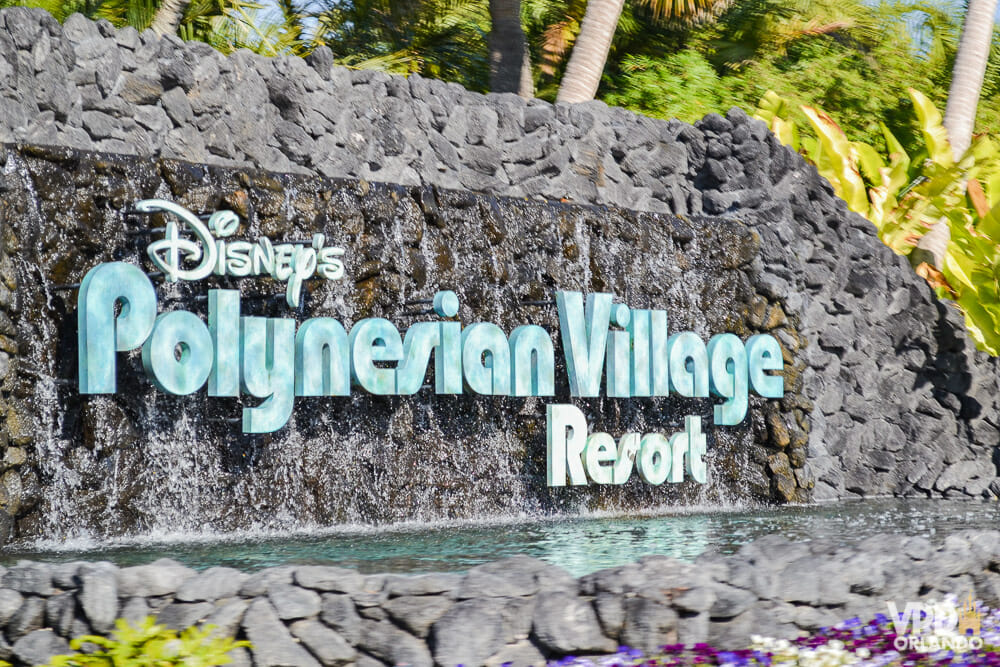 Foto da placa na entrada do hotel Disney's Polynesian Village Resort. O fundo da placa é de pedra e as letras são azul-claras.