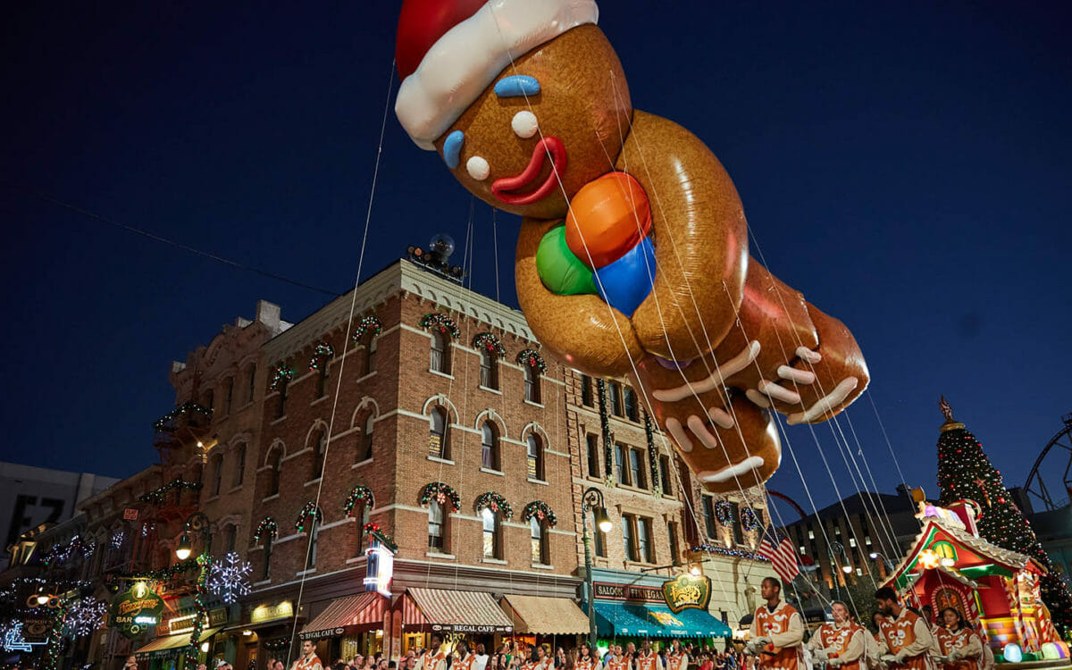 Foto de uma parada com balão em formato de Gingerbread Man, que faz parte das comemorações de Natal da Universal.