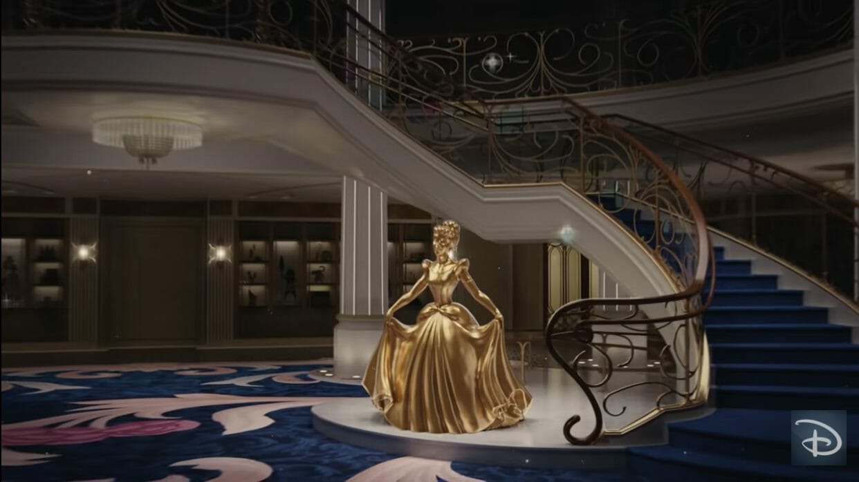 Imagem do novo navio Disney Wish, com estátua dourada da Cinderella ao lado da escadaria.