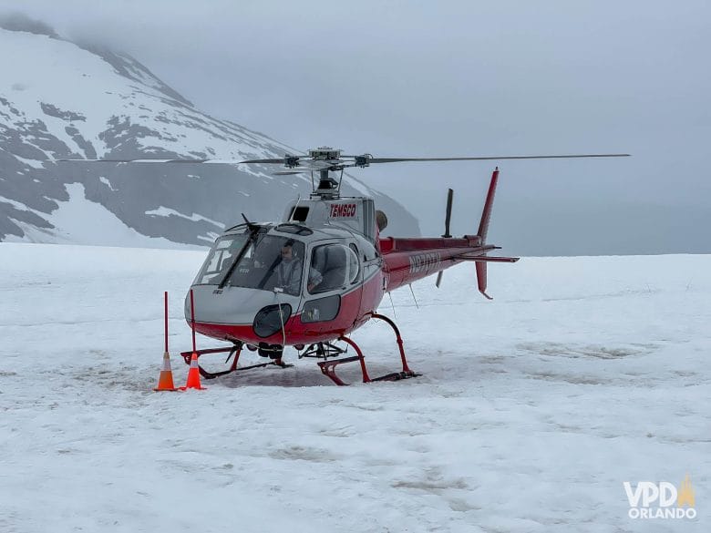 helicóptero vermelho pousando na neve em uma geleira no Alasca.