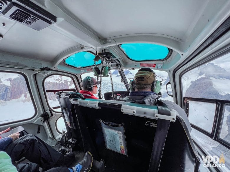 pessoas dentro de um helicóptero sobrevoando geleiras de neve no Alasca.