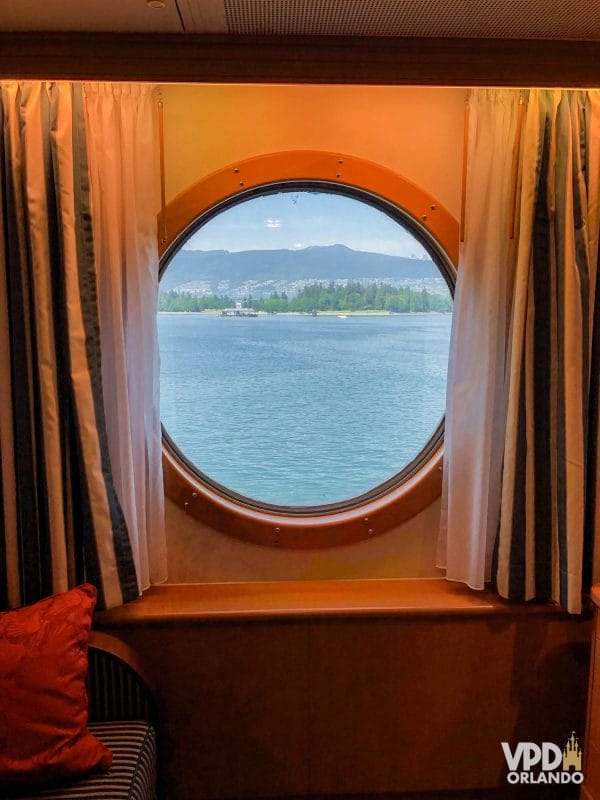 janela de uma cabine do navio da Disney, com mar e montanhas ao fundo.