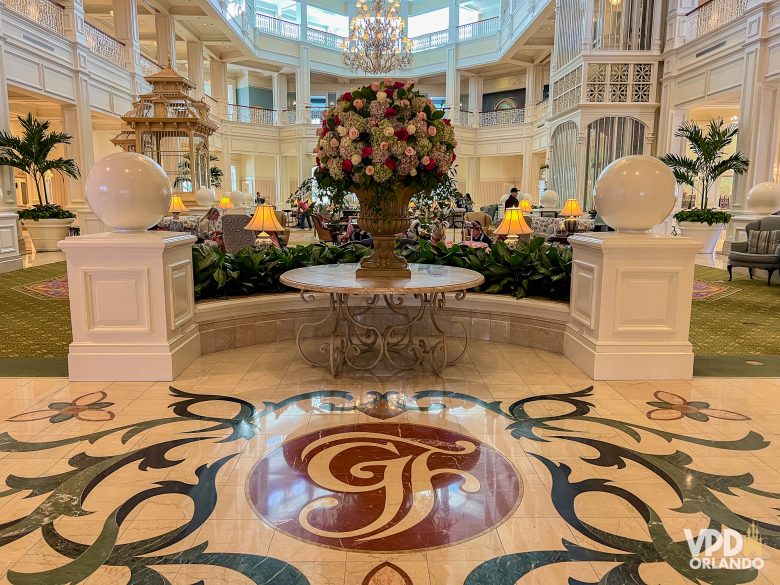 Lobby do grand floridian, com o GF esculpido no chão e um grande vaso de flores no centro