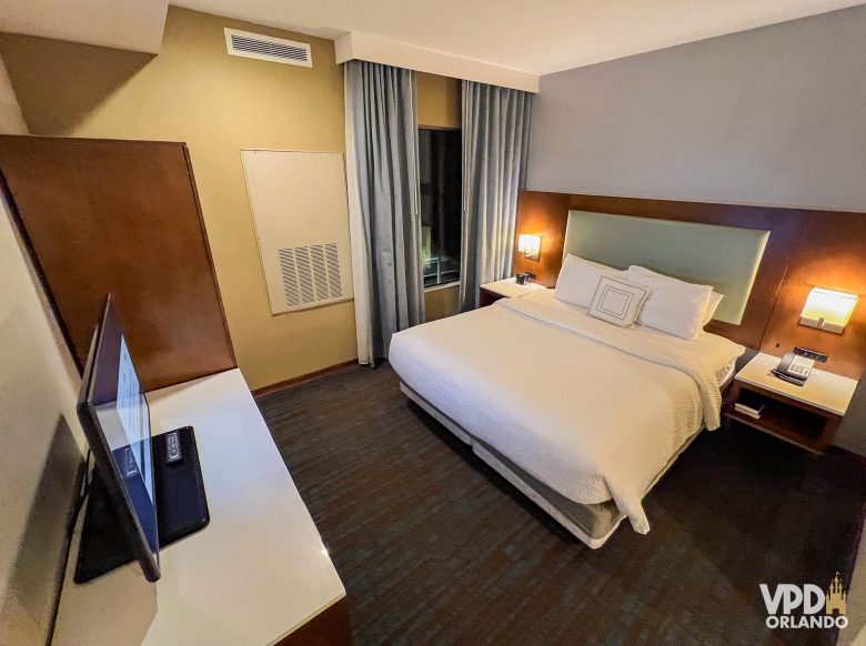 área do quarto do hotel Springhill Suites com cama, móveis e televisão